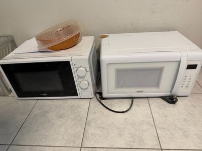 two microwaves that are sitting on the floor next to each other