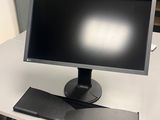 un écran d'ordinateur posé sur un bureau, avec une chaise à côté