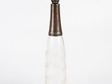 a glass bottle with a silver lid on a white surface