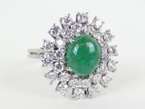 gros plan d'une bague avec une pierre verte entourée de diamants blancs
