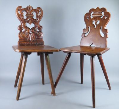 deux chaises en bois aux dossiers sculptés sont disposées côte à côte sur un fond gris