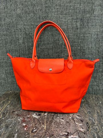 LONGCHAMP – Sac en toile orange pliable.
