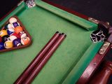 a pool table with a billiards rack and two cues in it