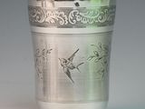 a silver cup with a bird on it on a table
