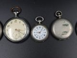 six antique pocket watches are lined up in a row on a black surface