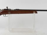 un fusil posé sur un socle transparent, devant un fond blanc