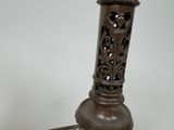 a metal candle holder that has a candle on top of it