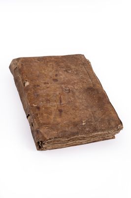 an old book is sitting on a white surface with a white background