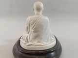 statue of a person sitting on a wooden base with a white background