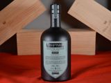 a bottle of alcohol sitting on a bed next to a wooden box