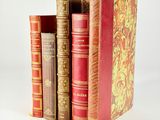 several old books are stacked on top of each other on a white surface