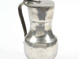 an antique silver pitcher on a white background with a bird on the handle
