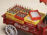 a toy man sitting in a coca cola cart