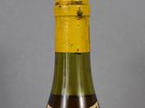 bottle of wine with a yellow cap and label on a grey background