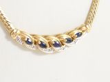 a close up of a gold necklace with blue stones on a mannequin