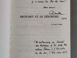 un livre ouvert, dont une page est recouverte d'une écriture manuscrite, posé sur une table