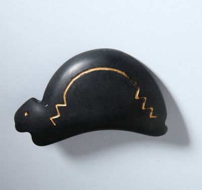sculpture noire et dorée représentant une tortue sur un fond blanc