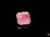 une pierre de quartz rose posée sur une surface noire