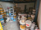 many buckets of paint sitting on the floor in a garage