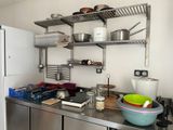 a kitchen with a stove, refrigerator, and shelves with pots and pans on it