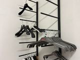 a rack with clothes hanging on it in the corner of a room