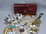 un sac à main rouge rempli de bijoux posé sur une surface blanche