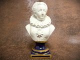 a white bust of a woman on a blue and gold pedestal