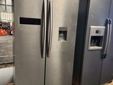 two large stainless steel refrigerators sitting on pallets in a warehouse