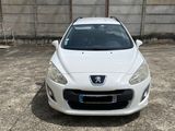 une voiture blanche garée sur un parking près d'une clôture