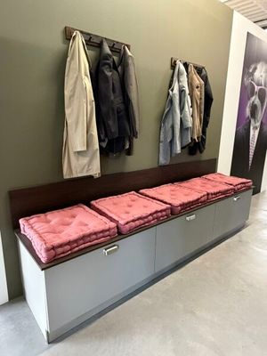 une photo d'un couloir avec un banc et un porte-manteau