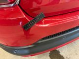 the rear end of a red car with a sticker on it ' s bumper