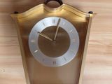 a gold clock on a wooden table with a brown handle