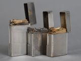 three silver lighters are lined up in a row on a gray surface