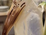 a ceramic bird that is sitting on top of a coffee pot