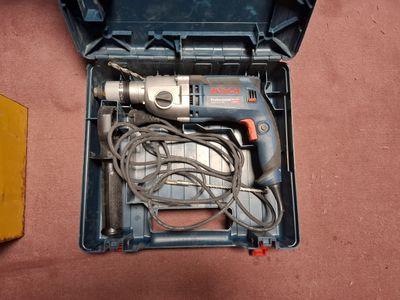 une perceuse dans une boîte à outils posée par terre