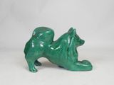 a small green statue of a dog on a white surface