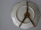 a white plate with a gold clock on top of it