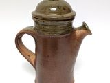 a brown coffee pot with a lid on a white surface