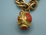 an image of a gold chain with a red bead on it