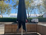 a black umbrella sitting on a wooden bench next to a parking lot