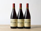 trois bouteilles de vin posées sur une table en bois