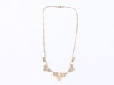 a gold necklace with a flower design on a white background