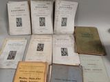 several old books sitting on top of a table next to a vase