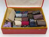 a red suitcase filled with assorted ties on a white surface