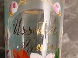 a glass with a flower painted on it sitting on a table