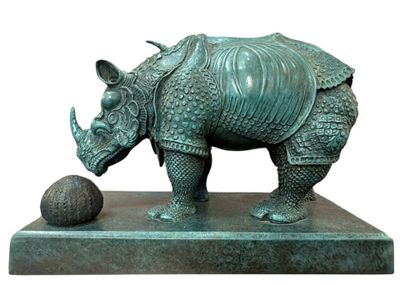 statue d'un rhinocéros tenant une balle, posée sur un socle