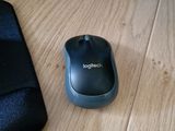 a computer mouse sitting on a wooden desk next to a cell phone