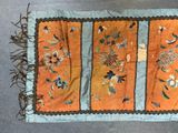 an orange and blue table runner with flowers and leaves on it