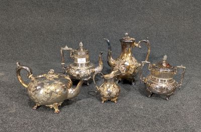 trois théières en argent et une cafetière posées sur une table