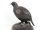statue d'un faisan posée sur un socle en bois, sur fond blanc